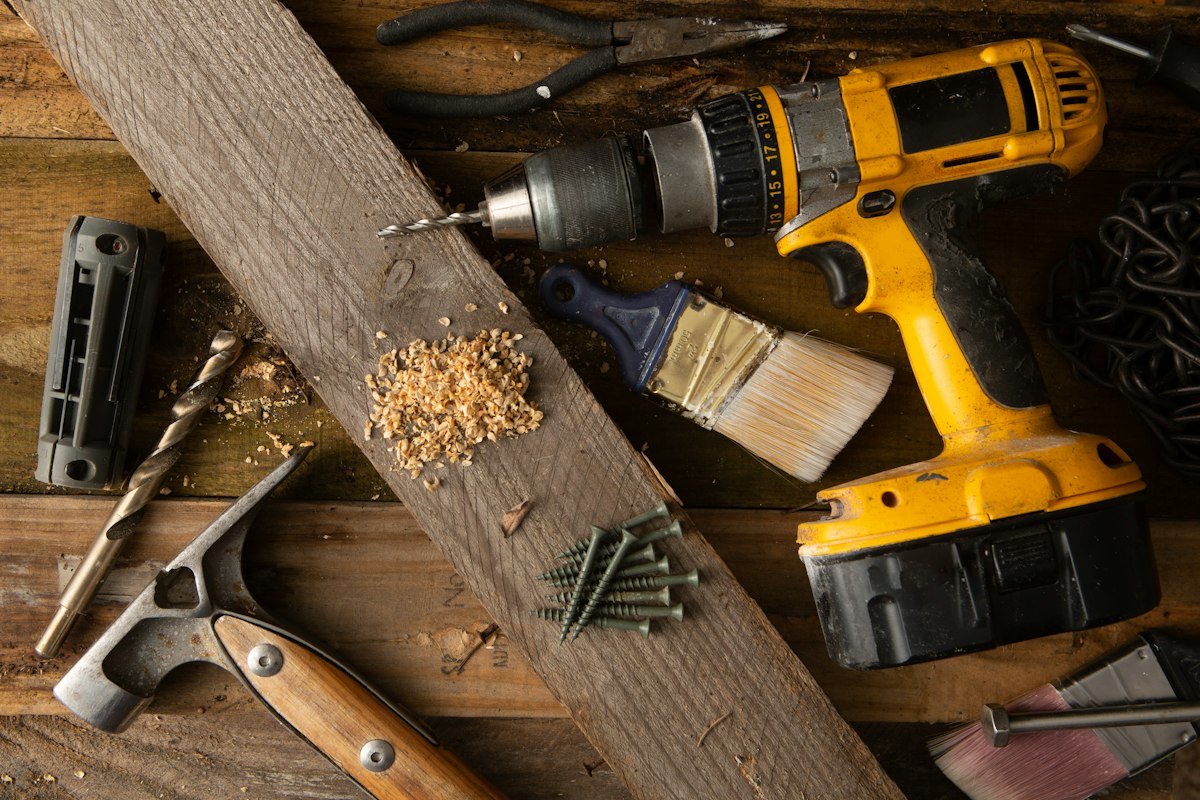 Hand tools and drill on a wooden work surface — illustrative photograph